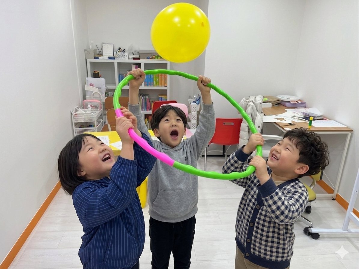 훌라후프로 풍선을 함께 받는 세 아이의 협력 놀이 장면